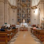 A serene church interior with people attending a religious ceremony led by a priest.