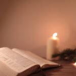 Open Bible with candle and festive greenery creates a serene ambiance.