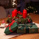 Cozy Christmas scene featuring red candles, gifts, and decorations on a wooden table.