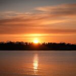 A stunning sunrise over Cove Island Park in Stamford, Connecticut, reflecting vibrant hues on the water.