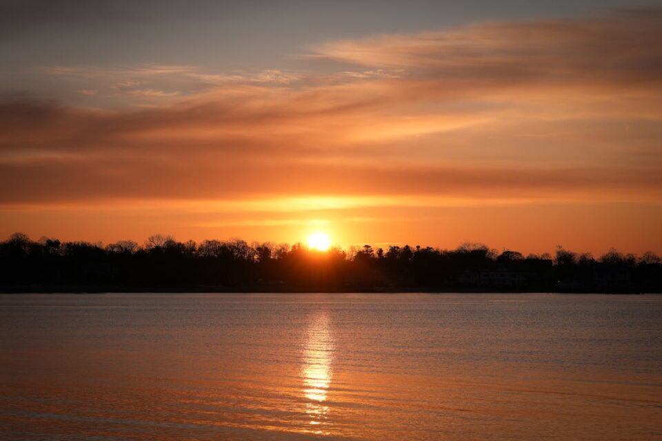 A stunning sunrise over Cove Island Park in Stamford, Connecticut, reflecting vibrant hues on the water.