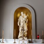 gold statue of man holding cross