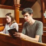 Two young adults reading the Holy Bible inside a church, reflecting faith and spirituality.