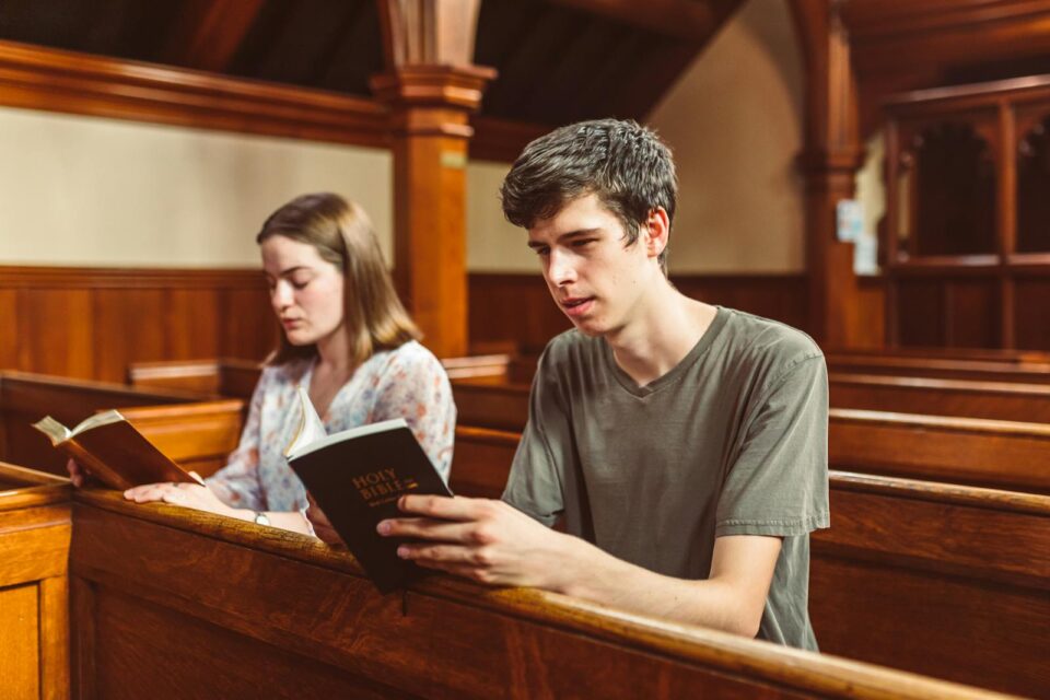 Two young adults reading the Holy Bible inside a church, reflecting faith and spirituality.