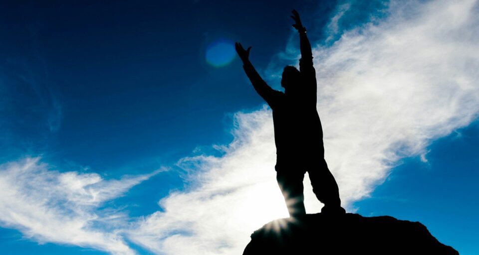 silhouette of man raising his hands under blue sky during daytime