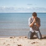 man kneeling down near shore