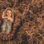 A nativity scene featuring a baby Jesus figurine surrounded by straw, symbolizing hope and tradition.