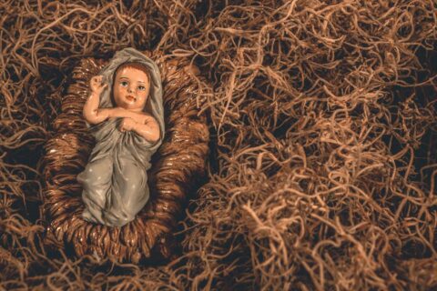 A nativity scene featuring a baby Jesus figurine surrounded by straw, symbolizing hope and tradition.