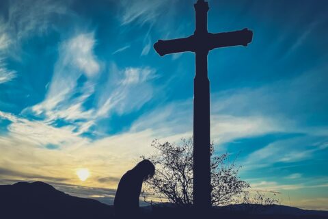 Snaga Isusova oprosta a person kneeling down in front of a cross