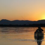 a person in a kayak on a lake at sunset