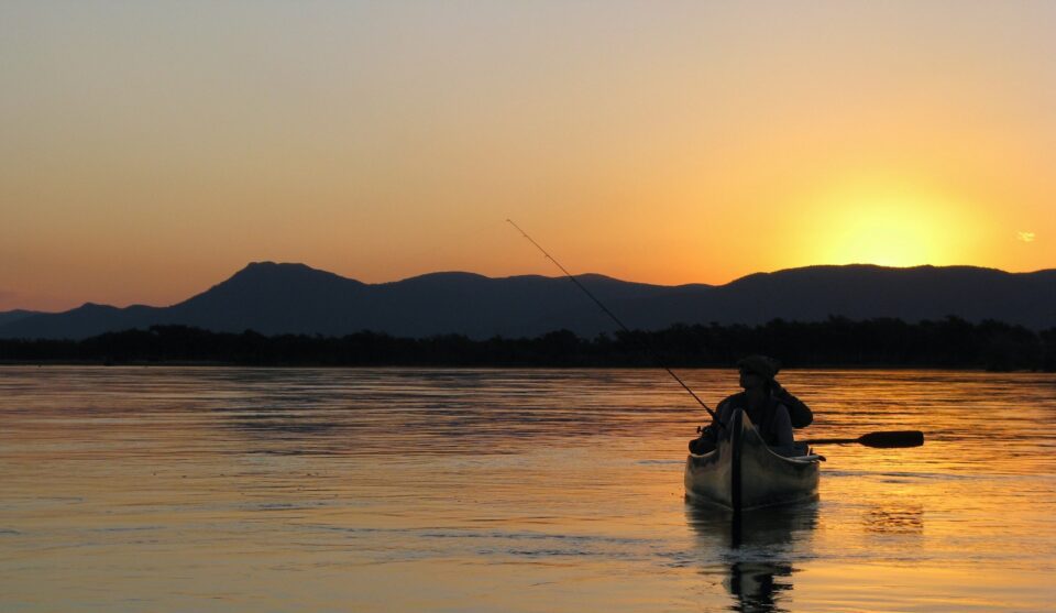 a person in a kayak on a lake at sunset