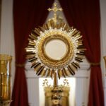 a golden cross and two candles in front of a window