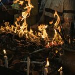People gather around flames and burning offerings.