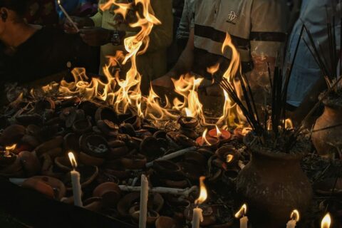 People gather around flames and burning offerings.
