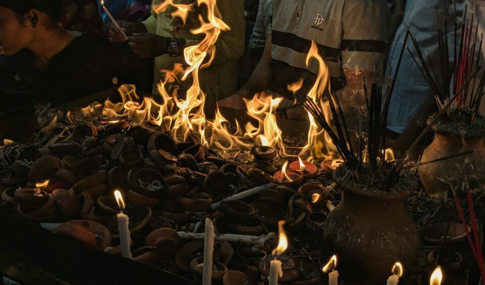 People gather around flames and burning offerings.