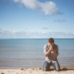 man kneeling down near shore