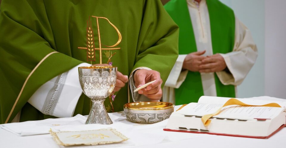 a priest is lighting a candle on a table