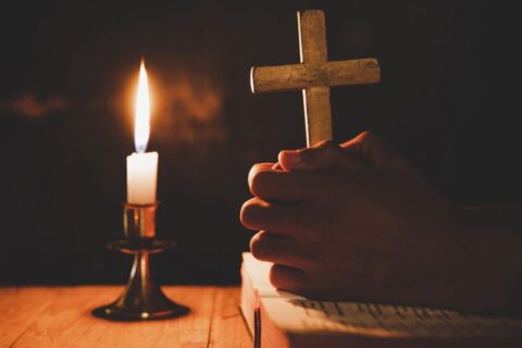 man praying on the Bible in the light candles selective focus. B