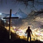 man standing near cross during night