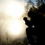silhouette of kneeling man