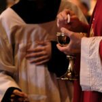 A priest is holding a glass of wine