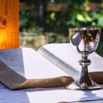 an open book and a chalice on a table