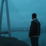 a man standing in front of a bridge at night