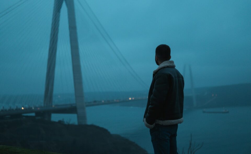 a man standing in front of a bridge at night