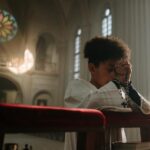 Child praying with rosary in a serene cathedral setting, sunlight through stained glass.