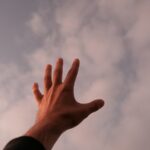 a person's hand reaching up into the sky