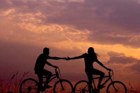 woman on bike reaching for man's hand behind her also on bike