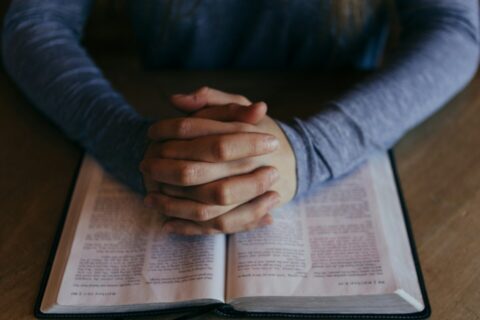 man holding his hands on open book