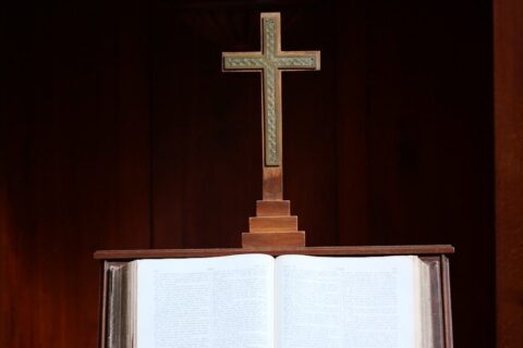 an open book with a cross on top of it