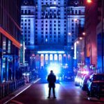 people walking on sidewalk near high rise buildings during night time