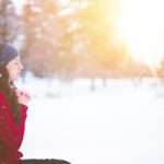 woman sitting with closed eyes surrounded by snow