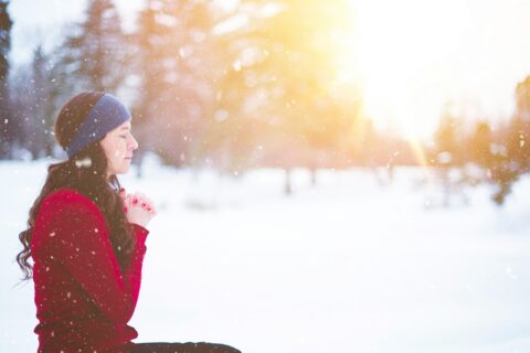 woman sitting with closed eyes surrounded by snow