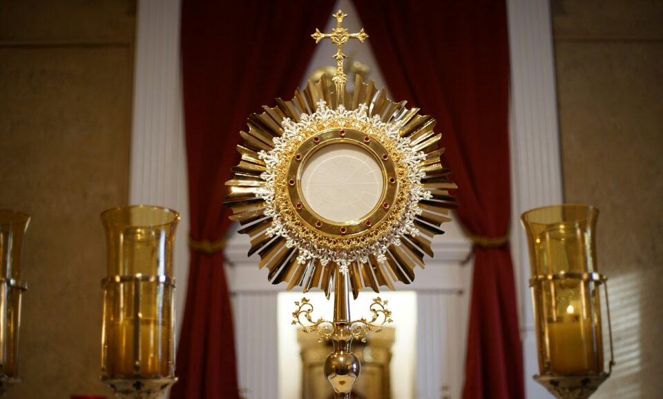 a golden cross and two candles in front of a window