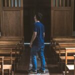 a man standing in a church looking at the pews