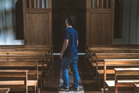 a man standing in a church looking at the pews