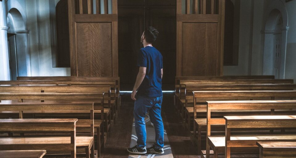 a man standing in a church looking at the pews
