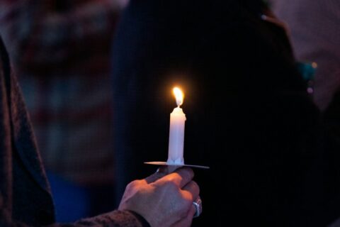 A person holding a lit candle in their hand