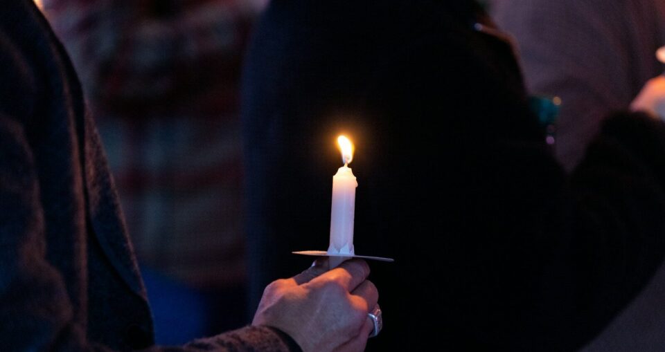 A person holding a lit candle in their hand
