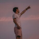 man in white t-shirt and brown pants standing on brown field during daytime