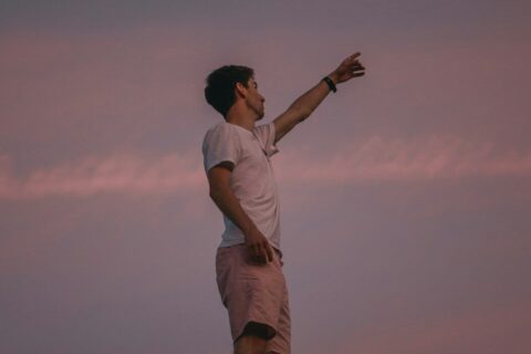 man in white t-shirt and brown pants standing on brown field during daytime