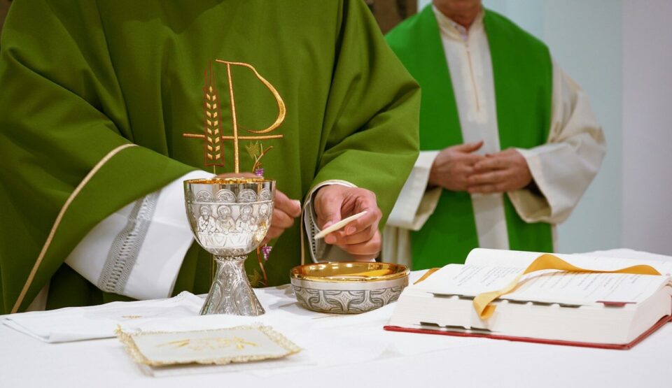 a priest is lighting a candle on a table