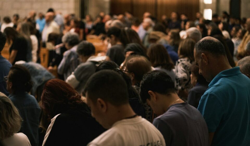 A crowd of people bowing their heads in prayer.