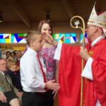 Biskup dijeli sakrament krizme dječaku u crkvi