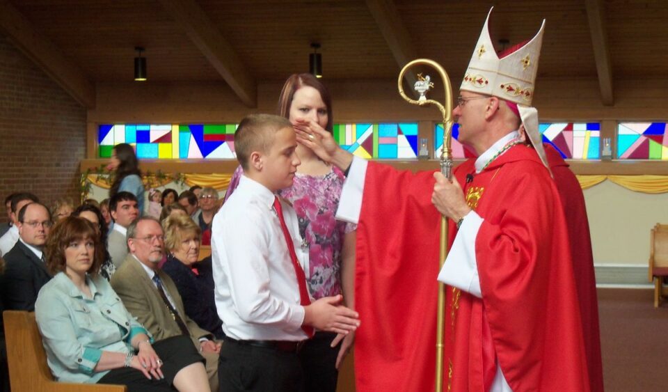 Biskup dijeli sakrament krizme dječaku u crkvi