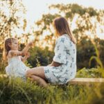 a woman and a little girl sitting on a bench