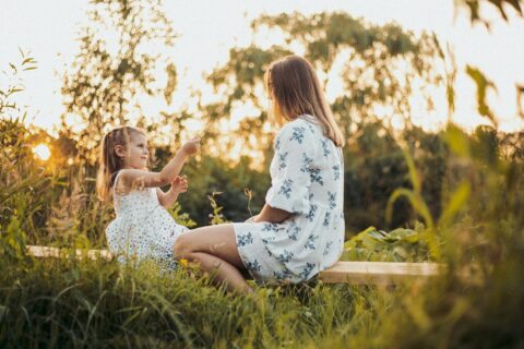 a woman and a little girl sitting on a bench